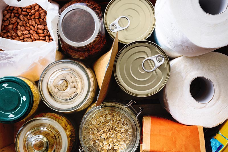 Close up of non-perishable food, canned goods and toilet paper.
